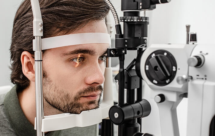 Man Having a comprehensive eye care exam, looking into an eye machine.