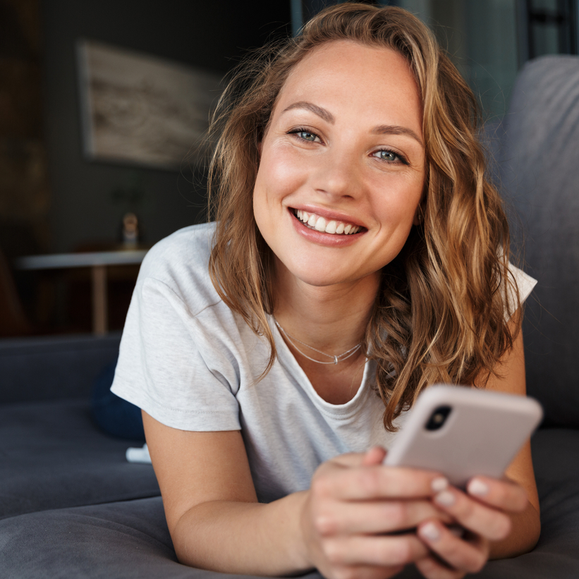 woman lying on couch with phone calling the lasik and refractive eye surgery clinic.